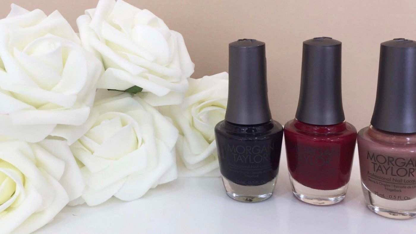 Esmaltes en tonos vino junto a rosas blancas